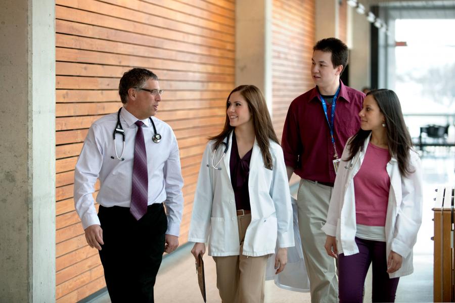 A group of students walking with a faculty member, down a hallway.